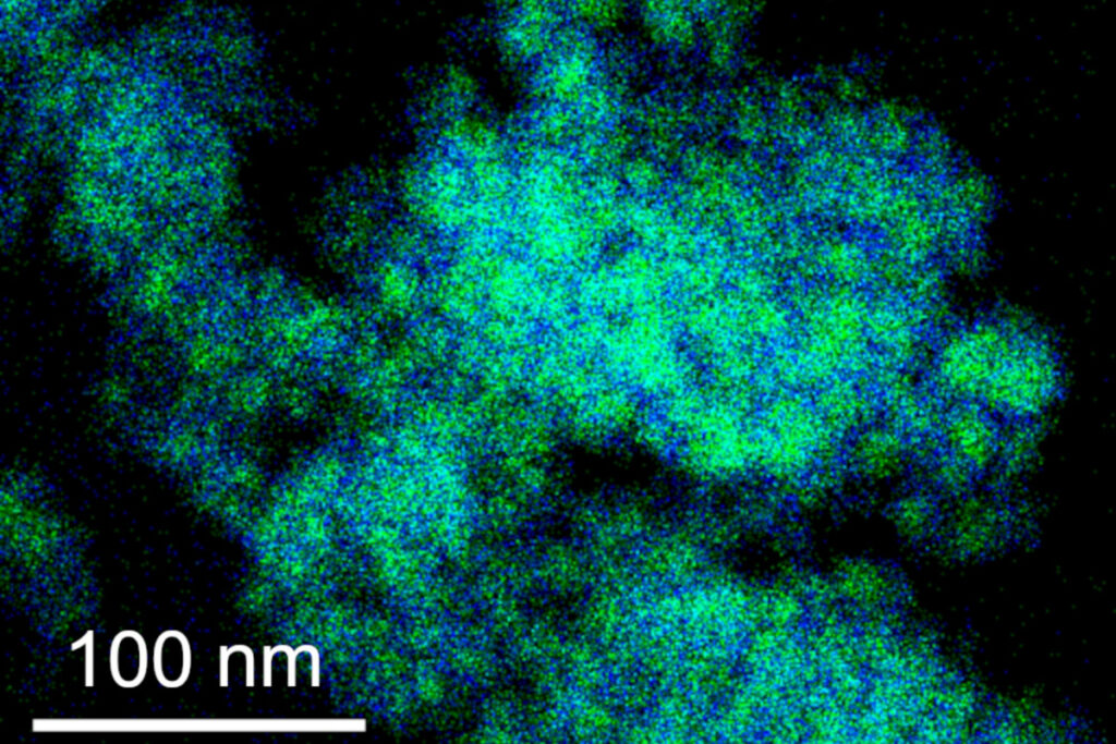 Wolke aus blauen und grünen Punkten auf schwarzem Hintergrund mit weißem Balken für die Größe: etwa ein Drittel des Bildes sind hundert Nanometer.